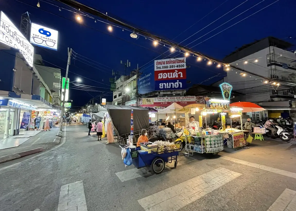 Street-food stalls lit up along Hua Hin night market at dusk